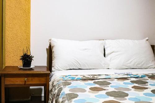 a bed with a white pillow and a nightstand at Hotel Ciudad Dulce Moniquira in Moniquirá