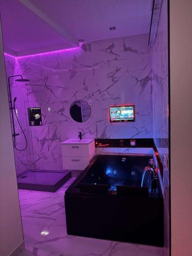 a bathroom with a tub and a sink and purple lighting at Suite Zen Amaryllis Jacuzzi TV Integrée Clim Wifi Béziers Centre Arrivée Autonome 24h24 in Béziers