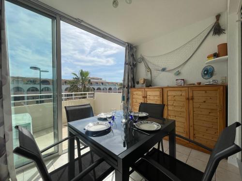 une salle à manger avec une table et des chaises et une grande fenêtre dans l'établissement T2 avec loggia vitrée, terrasse, parking à Sète - FR-1-338-589, à Sète