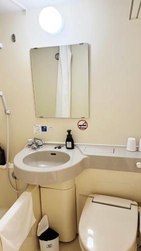 a bathroom with a sink and a toilet and a mirror at Yufuin Tabinokura in Yufuin
