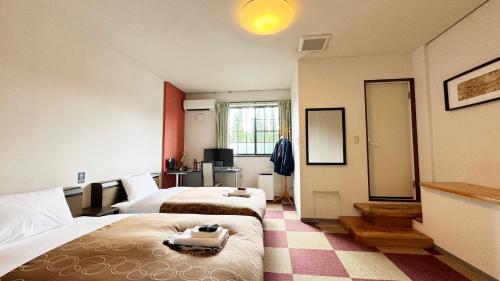 a hotel room with two beds and a mirror at Yufuin Tabinokura in Yufuin