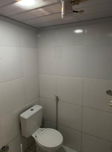 a white bathroom with a toilet and a ceiling at Suíte com entrada independente in Ubajara
