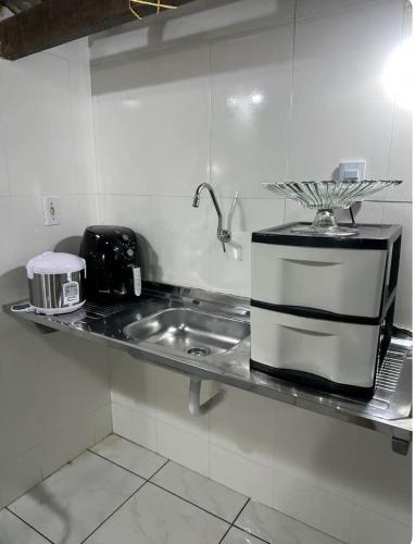 a kitchen counter with a sink and a microwave at Suíte com entrada independente in Ubajara