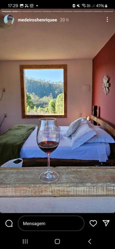 a glass of wine sitting on a table in a bedroom at Chalés Sitío dos Ventos in Lavras Novas