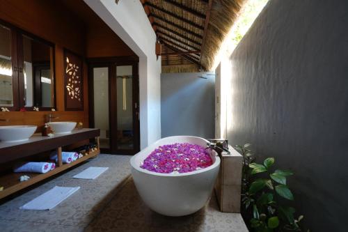 a bathroom with a bath tub filled with purple flowers at A Villa Gili Air in Gili Air