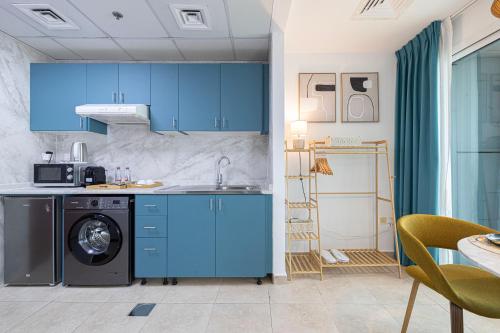 a kitchen with blue cabinets and a washing machine at Stunning Panoramic Sea & Marina City Skyline View in Dubai