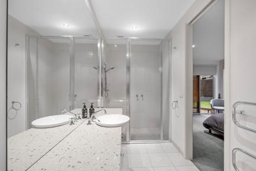 Un baño blanco con ducha y lavabo. en Sandcastle Haven, en Inverloch