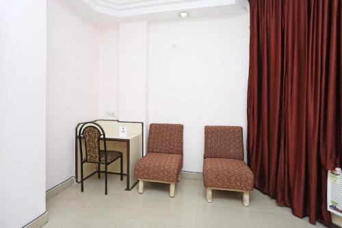 a room with two chairs and a table and a curtain at OYO Hotel Midtown in Raipur