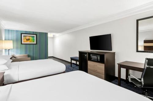 a hotel room with two beds and a flat screen tv at Best Western Slidell Hotel in Slidell