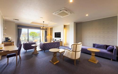 a living room with a couch and tables and chairs at Katakura Silk Hotel in Suwa
