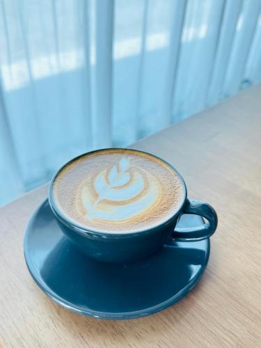 a cup of coffee sitting on a blue plate on a table at V1 boutique hotel in Kanchanaburi