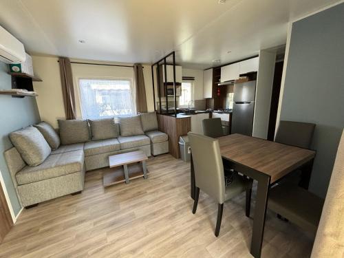 un salon et une cuisine avec un canapé et une table dans l'établissement Mobil home 253 Camping La Réserve 4 étoiles à Gastes, à Gastes