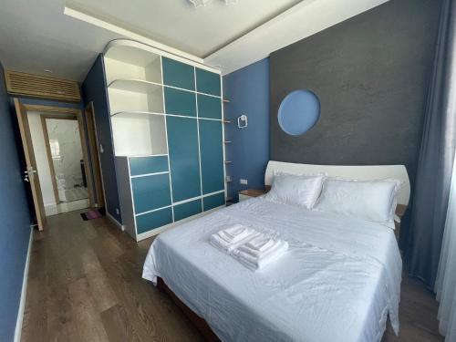 a bedroom with a white bed with a blue wall at Holiday Villa Novaworld Phan Thiet in Phan Thiet