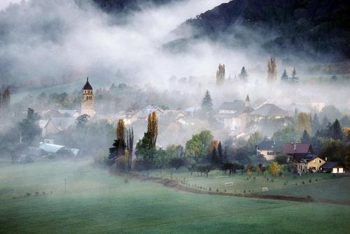 a painting of a village in the fog with a church at Le Gîte des Faucons in Faucon-de-Barcelonnette