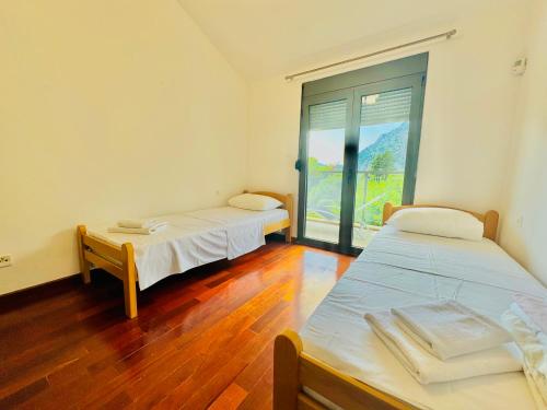 two beds in a room with a large window at Orahovac sunny port in Kotor