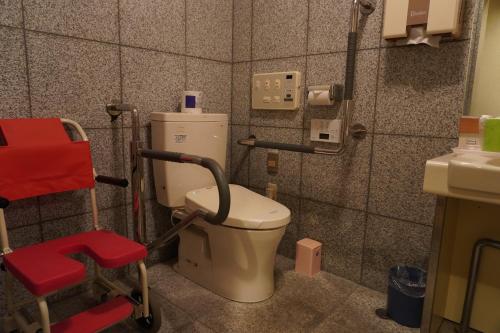 a bathroom with a toilet and a red chair at ホテルベイグランド国東 in Kunisaki