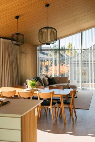 a living room with tables and chairs and a couch at Abodo Alpine Eco Villa Spa in Cardrona