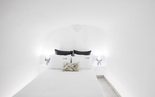 1 dormitorio con paredes blancas y 1 cama con almohadas en White Side Suites, en Oia