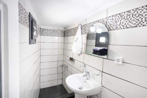 Un baño blanco con lavabo y espejo. en White Side Suites, en Oia