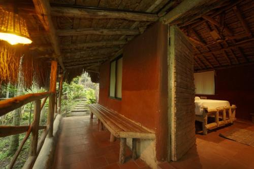 a wooden bench in a room with a bedroom at The Soul Marayoor Mudhouse - Munnar in Marayoor