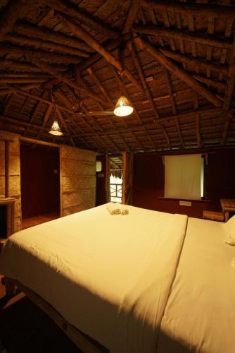 a large white bed in a room with a screen at The Soul Marayoor Mudhouse - Munnar in Marayoor