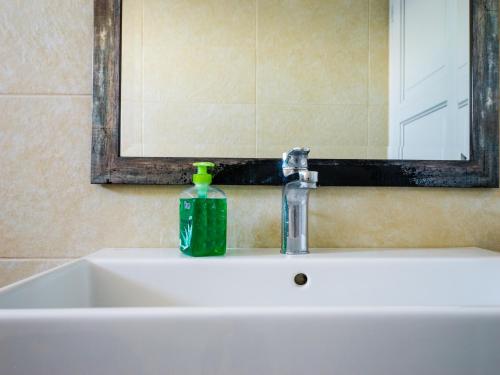 a bathroom sink with a soap bottle and a mirror at Heliades Maisonettes in Mithymna