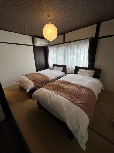 two beds in a room with a window at Sennichi House in Kanazawa