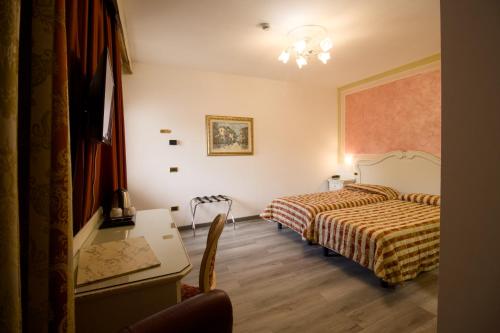 a hotel room with two beds and a desk at Hotel Villa Stucky in Mogliano Veneto