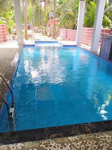 a swimming pool with blue water in a resort at Hotel Suryaprabha- Near Diveagar Beach in Diveagar