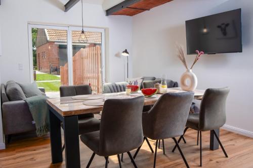 a dining room with a wooden table and chairs at Ferienwohnung Freia im historischen Gulfhof in Krummhörn