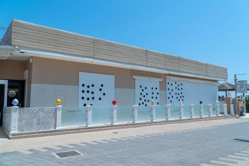 a building with a white fence in front of it at Frontemare 25 Beach Hotel in Ginosa Marina