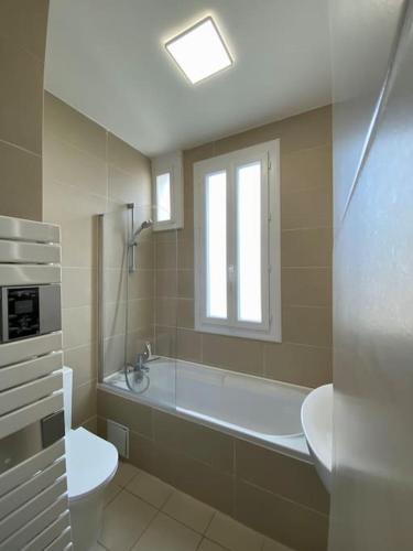 une salle de bain avec baignoire et toilettes et une fenêtre dans l'établissement Onlangs gerenoveerd appartement Vincennes Parijs, à Vincennes