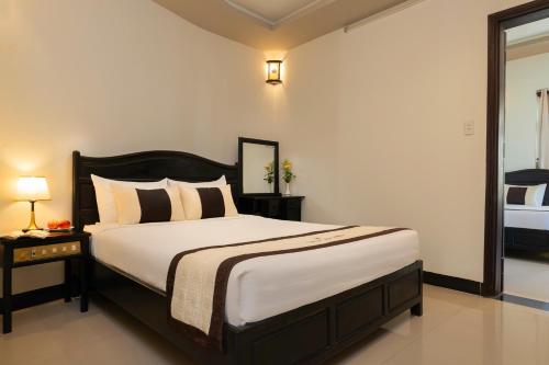 a bedroom with a large bed and a mirror at Green Tea Villa in Hoi An
