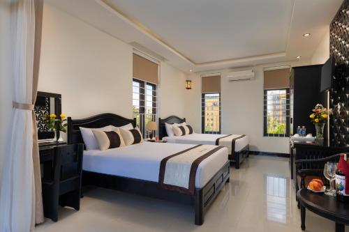a bedroom with two beds and a table at Green Tea Villa in Hoi An