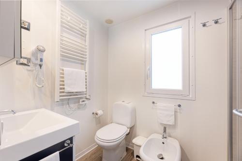 a white bathroom with a toilet and a sink at Camping Village Le Calanchiole in Capoliveri