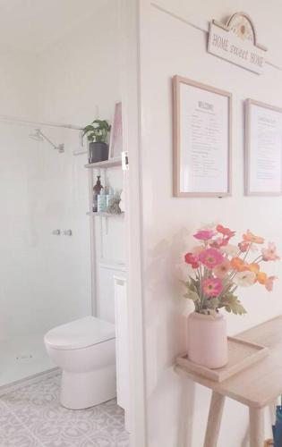 a bathroom with a toilet and flowers on a table at Willows Cottage on Anzac in Stanthorpe
