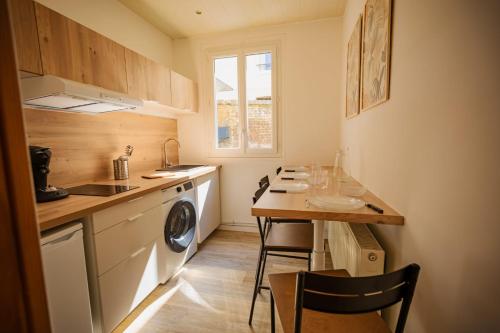 une petite cuisine avec une table et un lave-linge. dans l'établissement Le Nid Secret 5 Minutes a pied de la plage avec place Parking privée, au Havre