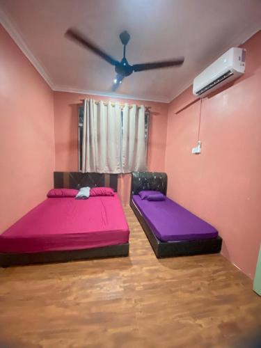 two beds in a room with a ceiling fan at VJ Homestay in Jasin