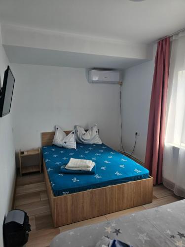 - une chambre avec un lit doté de draps bleus et une fenêtre dans l'établissement Vila Angelys, à Tuzla
