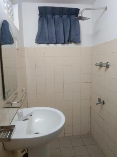 a bathroom with a white sink and a blue curtain at Fionn's Coconut Beach House in Negombo