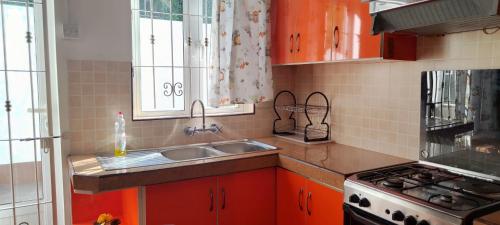 a kitchen with orange cabinets and a sink and a stove at R GARDEN Pointe Aux Sables in Pointe aux Sable