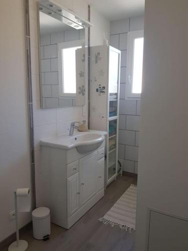 une salle de bain blanche avec un lavabo et un miroir dans l'établissement Maison pour 4 à 8 personnes à 15 min de Disney, à Nanteuil-lès-Meaux