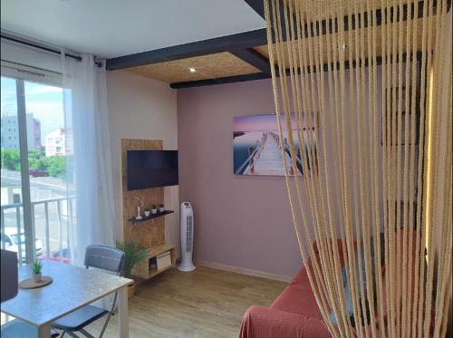 un salon avec un canapé rouge et une table dans l'établissement Studio charmant Cap d'Agde, au Cap d'Agde