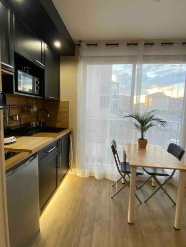 une cuisine avec une table et une salle à manger avec une fenêtre dans l'établissement Studio charmant Cap d'Agde, au Cap d'Agde