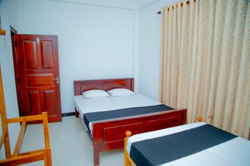 a small bedroom with two beds and a chair at Onara Guest in Anuradhapura