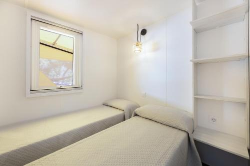 a room with two beds and a window at Camping Village Le Calanchiole in Capoliveri