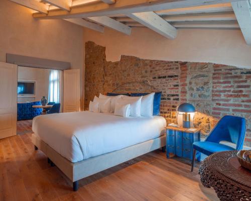 a bedroom with a large bed and a brick wall at La Monastica Resort & Spa in Borgo a Buggiano