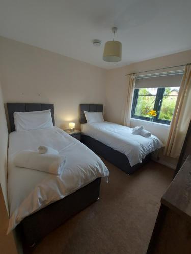 two beds in a room with a window at The Mews in Inverness