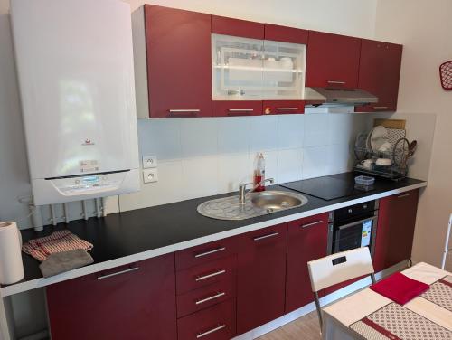une cuisine avec des armoires rouges et un évier dans l'établissement Résidence EYRAM, à Corbeil-Essonnes