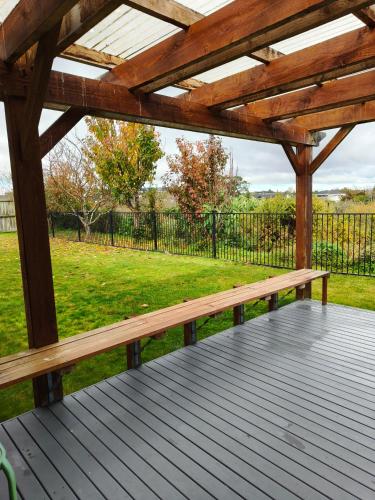 a wooden pergola with a bench on a deck at peaceful gully view home -4 bedrooms in Hamilton
